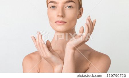 Cropped portrait of blonde woman framing her face with hands 110790720