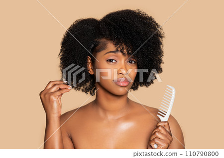 Sad black woman touching her curly hair and holding comb 110790800
