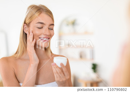 blonde woman applies facial cream embracing domestic skincare routine indoor blonde woman applies facial cream embracing domestic skincare routine indoor 110790802