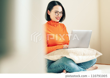 A woman watching a computer at home A woman watching a computer at home 110791005