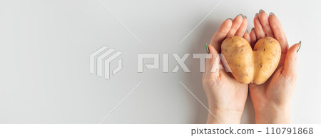 Heart shaped potatoes in hands on a white background. Valentine's day concept. Banner format. Heart shaped potatoes in hands on a white background. Valentine's day concept. Banner format. 110791868