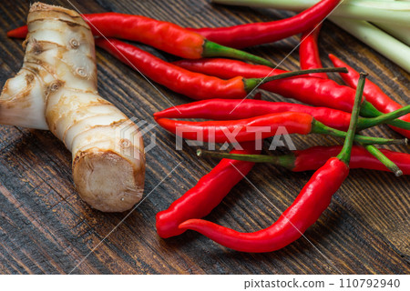 Galangal root, hot mini chili peppers with lemongrass on wooden table Galangal root, hot mini chili peppers with lemongrass on wooden table 110792940