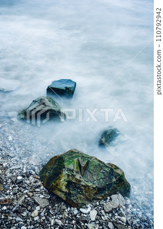 Row of boulders in foam of waves Row of boulders in foam of waves 110792942