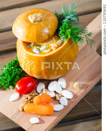 Tasty homemade pumpkin soup puree served in pumpkin at wooden desk Tasty homemade pumpkin soup puree served in pumpkin at wooden desk 110793691