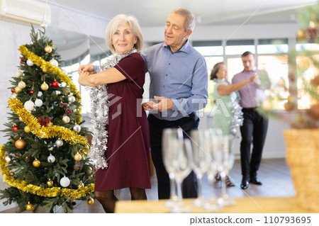 In studio decorated for New Year, elderly couple perky dance pair discofox. Champagne for guests In studio decorated for New Year, elderly couple perky dance pair discofox. Champagne for guests 110793695