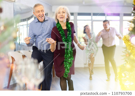In studio decorated for New Year, elderly man and woman perky dance pair discofox. 110793700