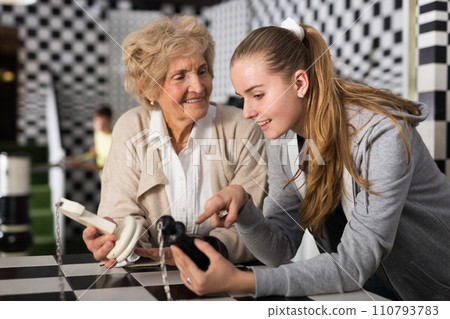 Grandmother and granddaughter solving chess conundrum in escape room 110793783