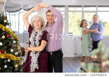 Positive middle-aged man dancing playful Latin dance bachata with mature female partner during celebration Christmas and New Year in choreography studio Positive middle-aged man dancing playful Latin dance bachata with mature female partner during celebration Christmas and New Year in choreography studio 110793814