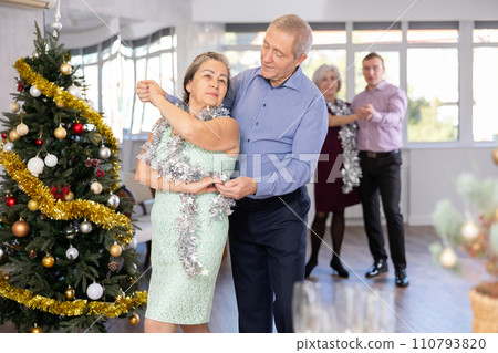 Happy mature woman enjoying impassioned merengue with male partner in dance room during celebration Christmas and New Year. Social dancing concept Happy mature woman enjoying impassioned merengue with male partner in dance room during celebration Christmas and New Year. Social dancing concept 110793820