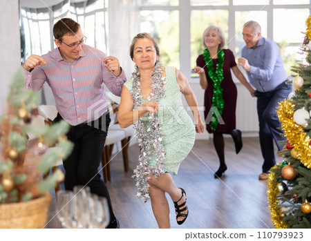 Group of adult active people dancing twist or rock and roll dance in dance hall during celebration Christmas and New Year 110793923