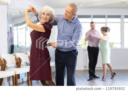 Happy mature woman enjoying impassioned merengue with male partner in dance class. Social dancing concept 110793932