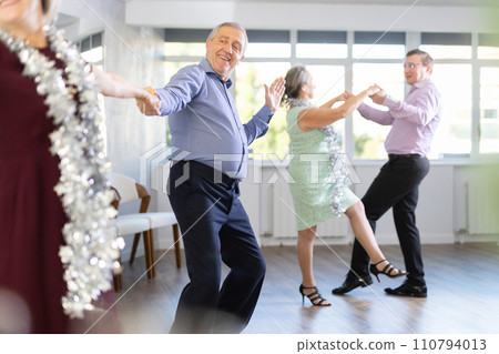 In studio decorated for New Year, elderly man and woman perky dance pair discofox. 110794013
