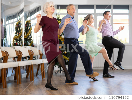 Group of elderly people with middle-aged man perform Irish folk dance during New Year party 110794132