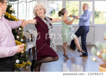 Smiling adult lady in elegant clothes dancing in couple latin dance, energetic and fast jive in dance salon during celebration Christmas and New Year 110794171
