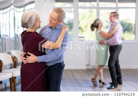 Elderly woman is dancing slow unhurried dance in hugs arms of her senior male partner. 110794229