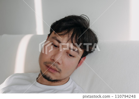 Close up face of lonely man feeling depressed and bored in low light room. Close up face of lonely man feeling depressed and bored in low light room. 110794248