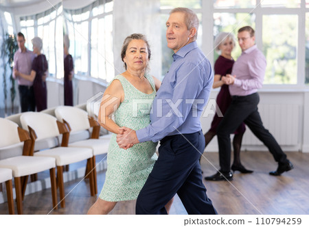 Senior man and elderly woman are dancing classic version of waltz in couple Senior man and elderly woman are dancing classic version of waltz in couple 110794259
