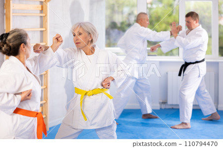 Two mature women in kimono practice painful blows during karate lessons 110794470