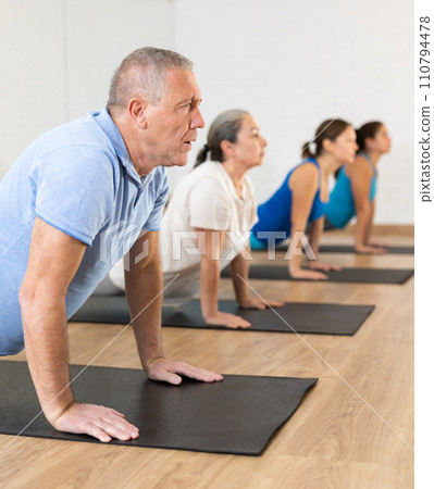 Group of young mature old people in sportswear exercising Pilates while stretching on mats in rehabilitation center Group of young mature old people in sportswear exercising Pilates while stretching on mats in rehabilitation center 110794478