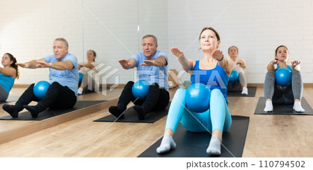 Middle-aged woman practicing pilates with ball in gym area Middle-aged woman practicing pilates with ball in gym area 110794502
