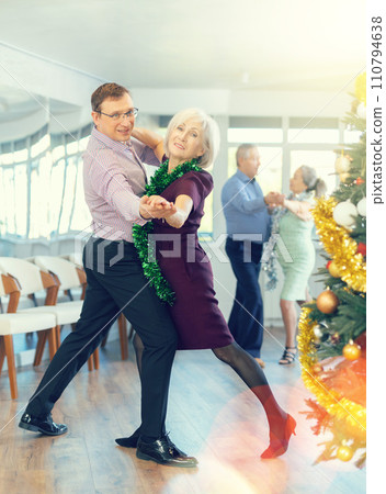 Middle-aged man and elderly woman dancing contemporary discofox in couple in New Year atmosphere 110794638