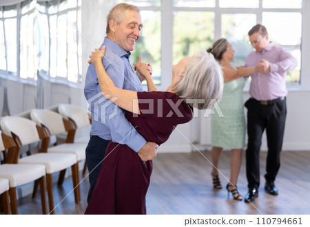 Pairs of mature amateur dancers enthusiastically performs romantic tango dance in dance salon 110794661