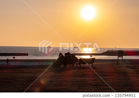 People gathering by the sea at sunset 110794951