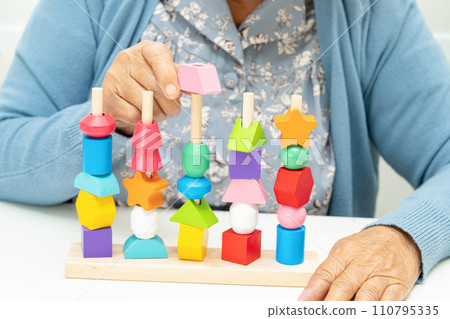 Alzheimer disease AD, Asian elderly woman patient suffering from dementia learn practical motor skills rehabilitation. Alzheimer disease AD, Asian elderly woman patient suffering from dementia learn practical motor skills rehabilitation. 110795335