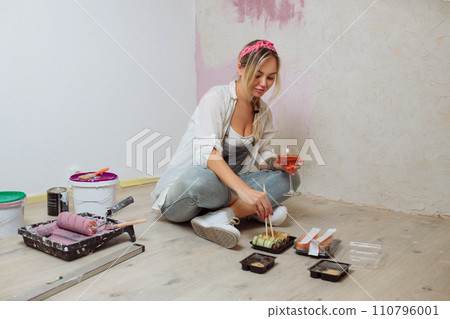 Sexy girl designer eats sushi on the construction site. painter has lunch after work.Concept interior design and room repair Sexy girl designer eats sushi on the construction site. painter has lunch after work.Concept interior design and room repair 110796001