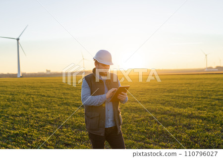 Businessman checking on wind turbine energy production 110796027