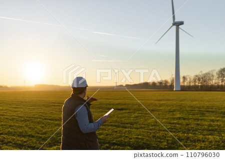 Businessman checking on wind turbine energy production 110796030