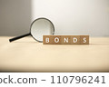 Fund and bond investment. Bond investment planning and economic data analysis. Small wooden blocks and magnifying glasses. 110796241