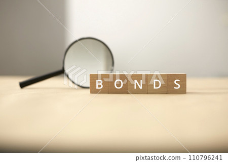 Fund and bond investment. Bond investment planning and economic data analysis. Small wooden blocks and magnifying glasses. 110796241