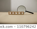Fund and bond investment. Bond investment planning and economic data analysis. Small wooden blocks and magnifying glasses. 110796242