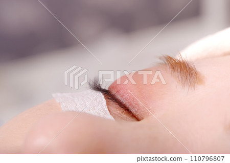 A young woman having false eyelashes glued on 110796807