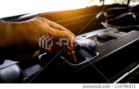 The auto mechanic pulls the dipstick to check the engine oil level 110796831
