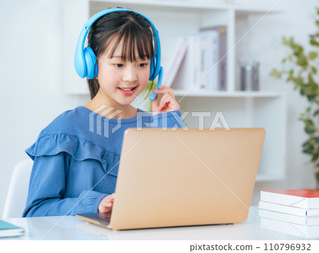 Girl wearing headphones and studying on a laptop 110796932