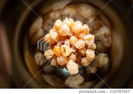 Close focus on small dried longans preserved inside glass jar. 110797047