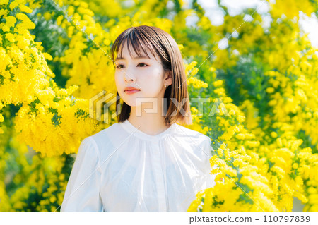 Young woman surrounded by mimosa 110797839