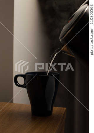 Pour hot water from an electric kettle into a cup. 110800568