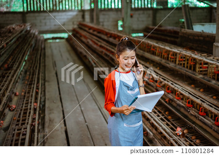 beautiful female farmer calls with cell phone and see clipboard beautiful female farmer calls with cell phone and see clipboard 110801284