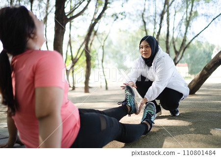 asian woman helping sprained ankle female friend 110801484