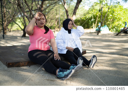 sporty asian women sitting wiping sweat 110801485