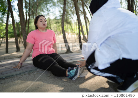 hijab woman helping twist ankle female friend hijab woman helping twist ankle female friend 110801490