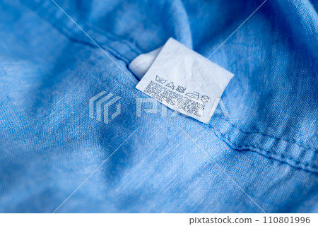 Clothing label on light blue garment, top view Clothing label on light blue garment, top view 110801996