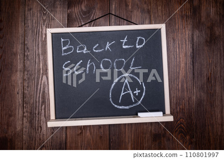 School grade. Small blackboard with chalked BACK TO SCHOOL with letter A and plus symbol on wooden wall School grade. Small blackboard with chalked BACK TO SCHOOL with letter A and plus symbol on wooden wall 110801997
