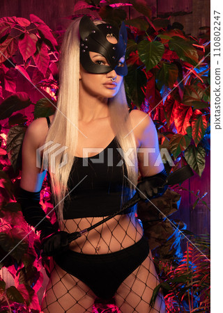 Sexy woman in cat mask. Lady with a leather whip. BDSM toys for role-playing sexual games with domination and submission 110802247