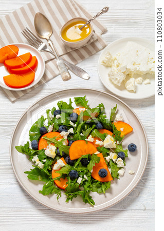 arugula persimmon cheese berries salad, top view arugula persimmon cheese berries salad, top view 110803034
