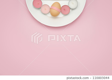 Chicken egg decorated with pink ribbon on a white plate with tea candles on pink monochrome background. Copy space simple pastel rustic background for traditional Easter holiday card Chicken egg decorated with pink ribbon on a white plate with tea candles on pink monochrome background. Copy space simple pastel rustic background for traditional Easter holiday card 110803044