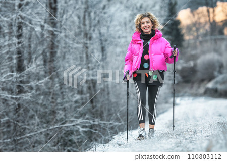 Sporty woman practices nordic walking in the cold Sporty woman practices nordic walking in the cold 110803112